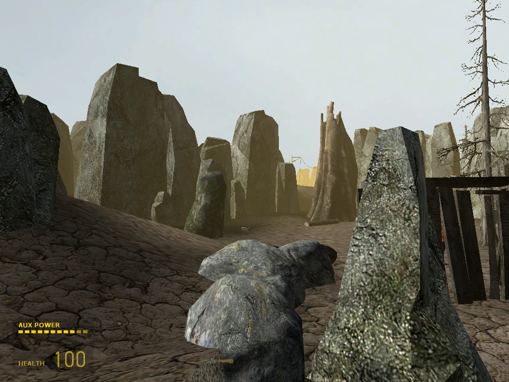 A Source Engine screenshot displaying an arid desert with cracked mud ground, dead trees, and strange stone features.